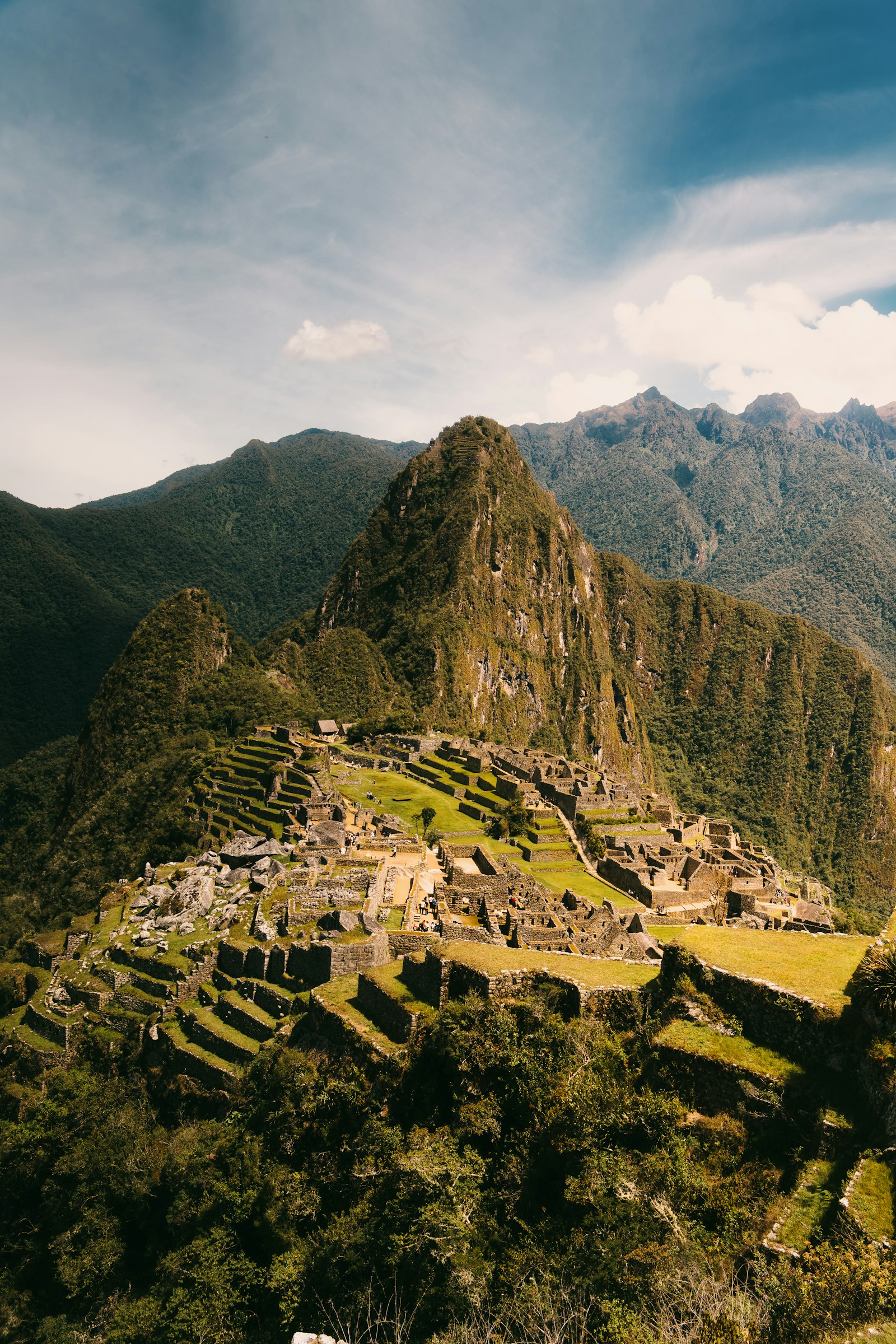 Stone terraces of Machu Picchu in early mist with green Andean peaks behind